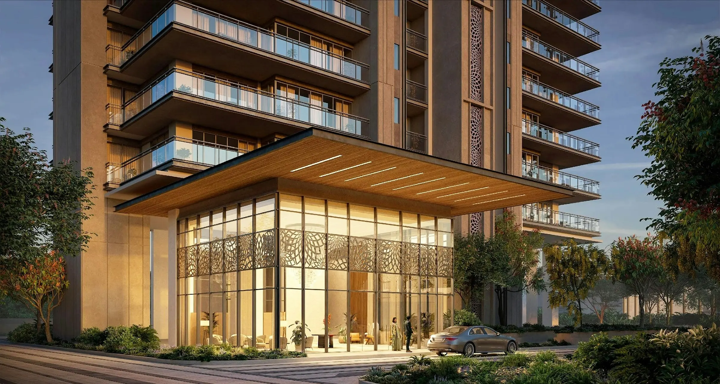 Modern stone-clad apartment building with a glass-walled lobby glowing at sunset